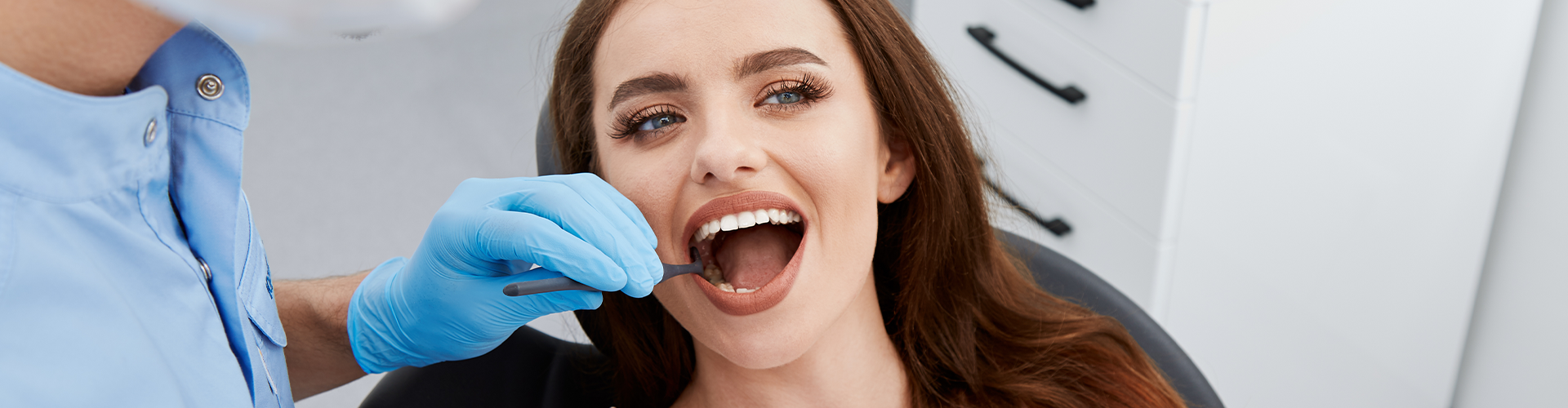 gloved hands holding dental tool in patient's mouth